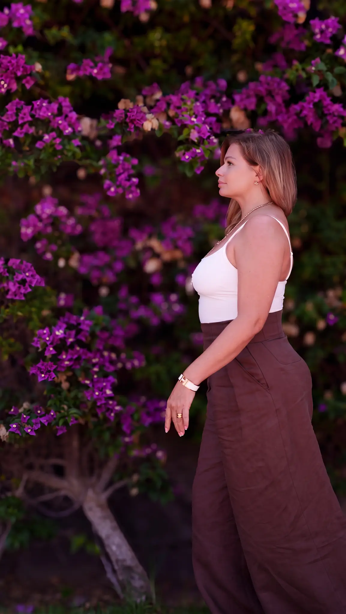 Nataliya geht im Abendlicht an einer blühenden Bougainvillea entlang