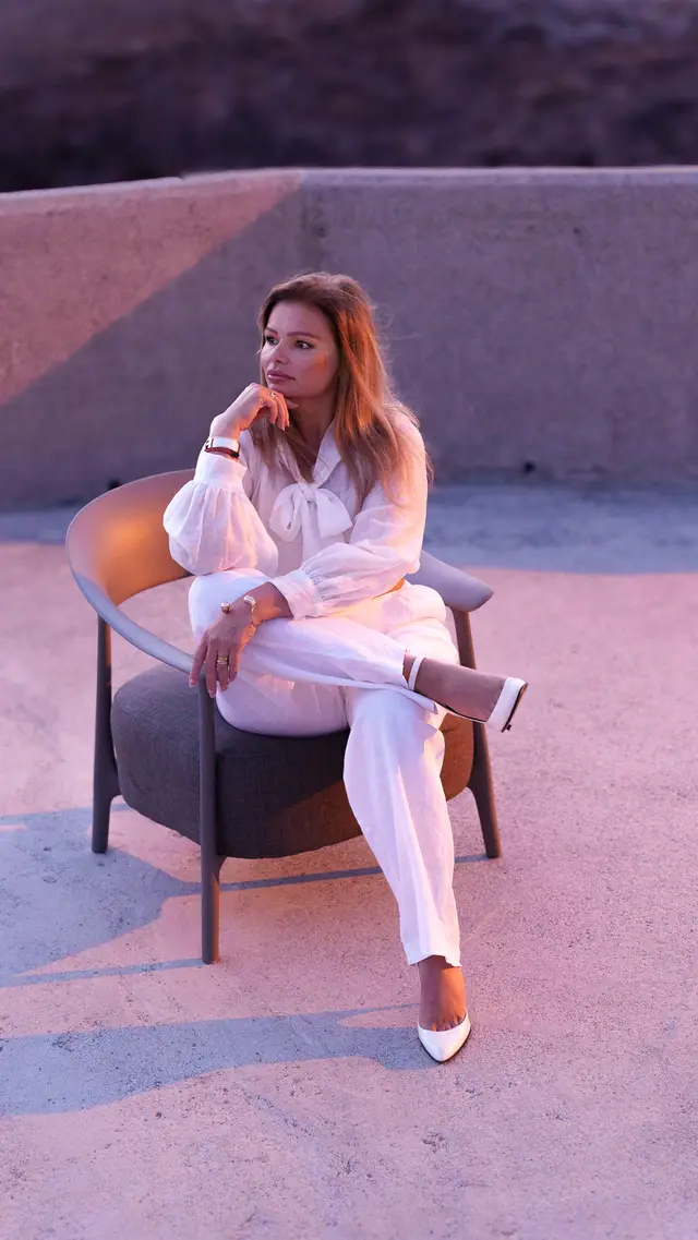 Nataliya sitzt im Abendlicht auf einer Terrasse, nachdenklich die Hand am Kinn